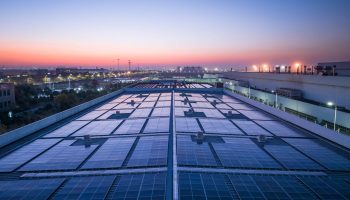Photo Looking Along A Commercial Rooftop, Covered In Solar Panels.
