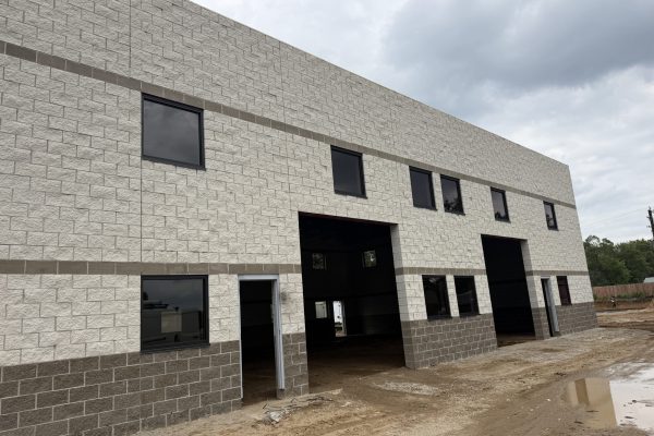 New commercial warehouse building under construction with masonry walls, overhead door openings, and completed exterior façade.