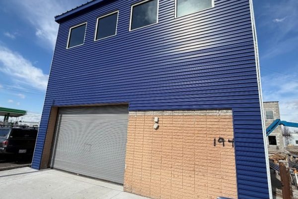 Completed exterior of Wash Pointe car wash facility with blue metal siding, garage bay, and modern commercial construction finish.