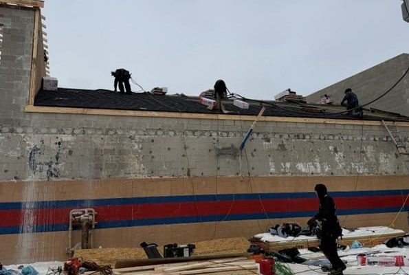 Roofing crew installing materials on Wash Pointe car wash structure during winter construction conditions.