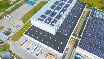 Photo Of Buildings On The Outskirts Of A City, With Solar Arrays On The Roofs.