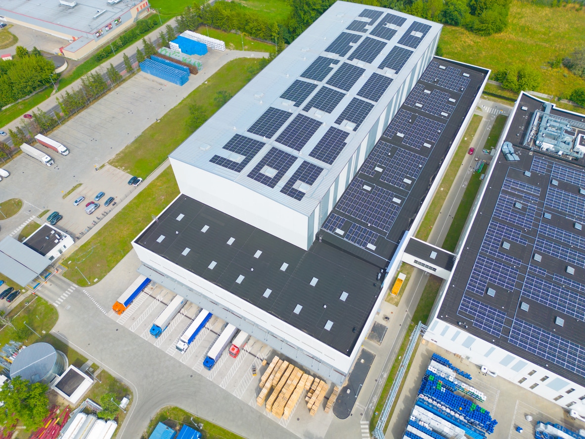 Photo of buildings on the outskirts of a city, with solar arrays on the roofs.