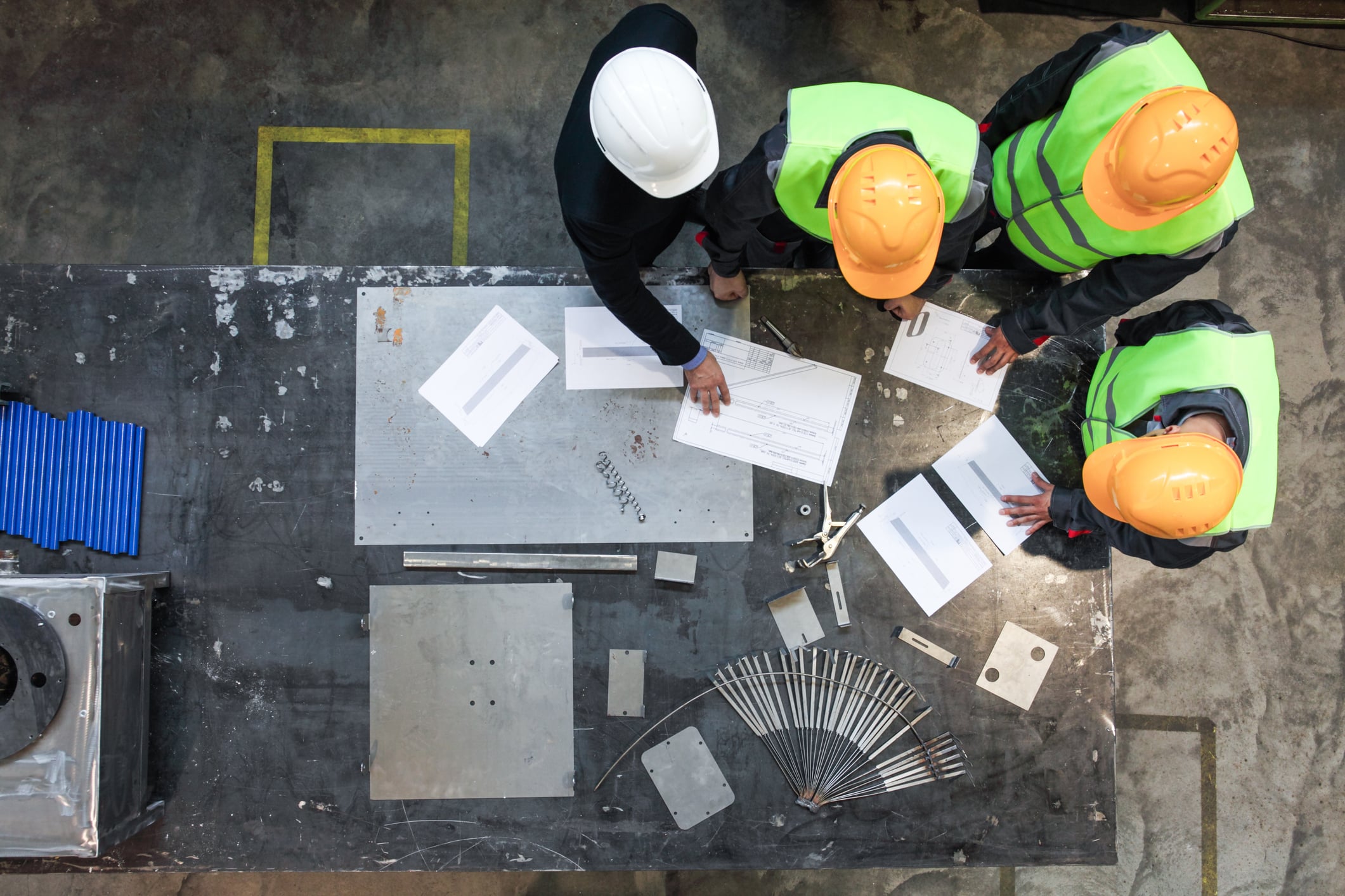 A small team of architects and engineers looking over some blueprints, with a laptop nearby.