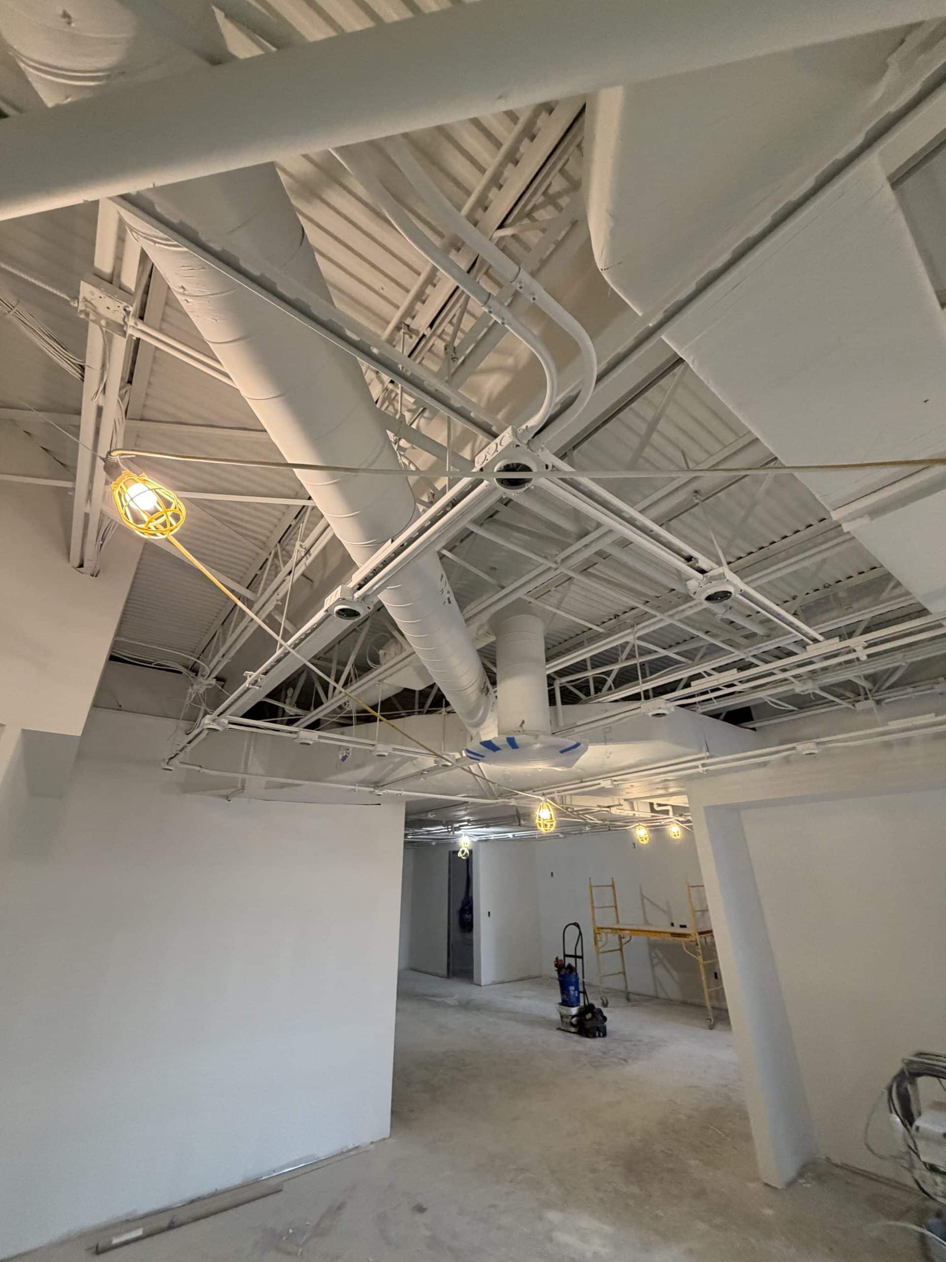 Commercial interior under construction with exposed HVAC ductwork and steel ceiling, a Schonsheck build-out in Michigan