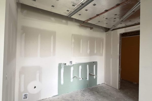 Commercial interior build-out with insulated HVAC ductwork, unfinished drywall, and utility rough-ins during construction.