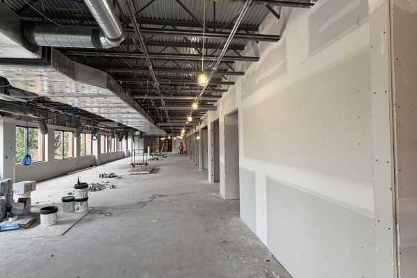 Commercial interior renovation in progress with exposed structural steel, HVAC ductwork, and newly installed drywall partitions.