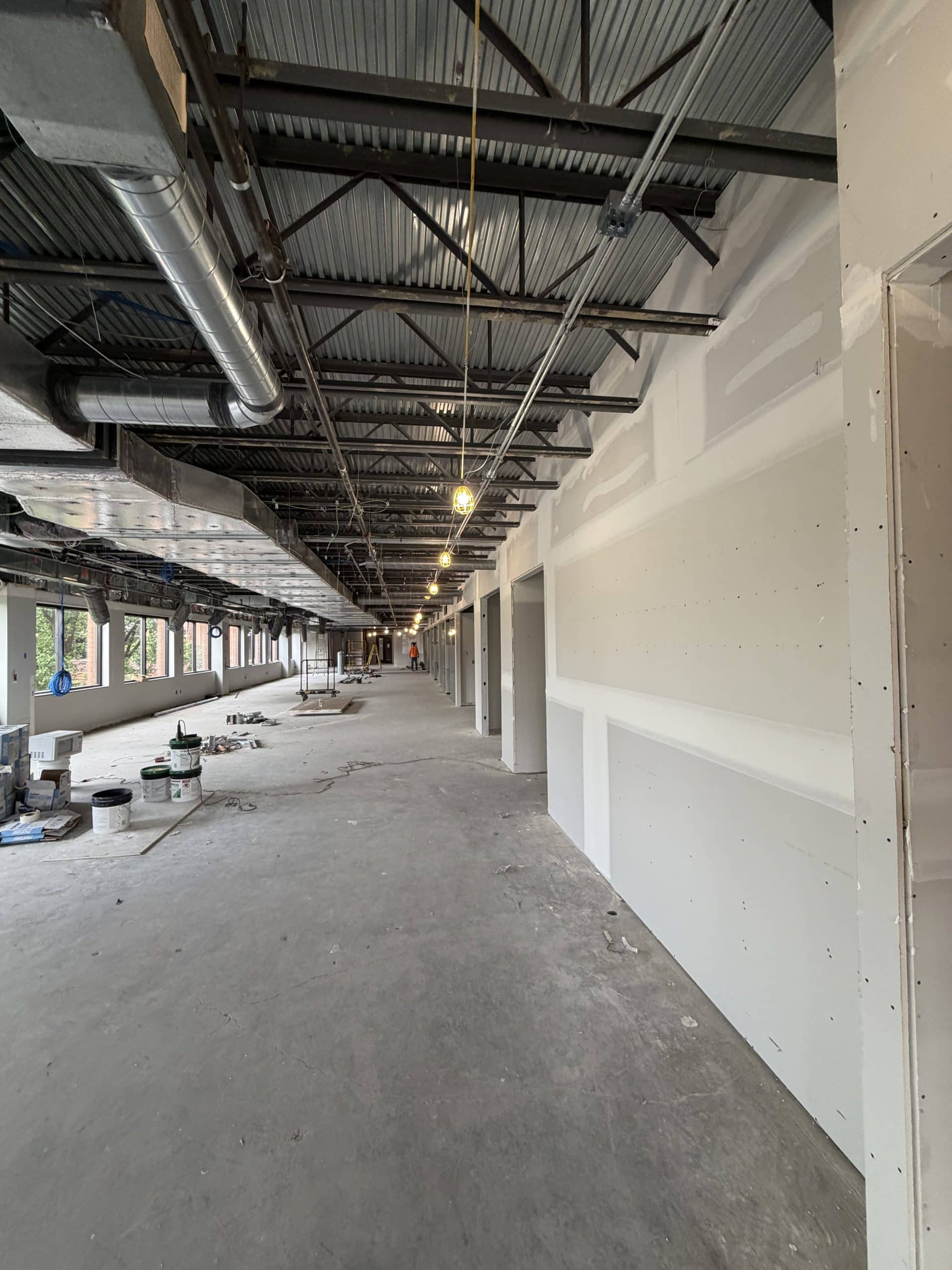 Commercial interior renovation in progress with exposed structural steel, HVAC ductwork, and newly installed drywall partitions.