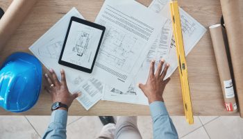 Two construction professionals reviewing plans on a tablet at an active commercial jobsite.