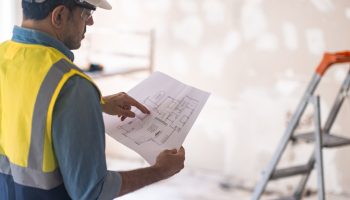 Commercial contractor reviewing building plans at an active construction site.