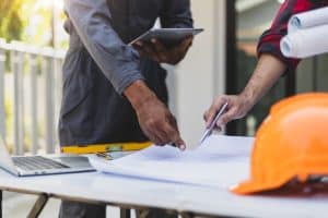 Business owner and commercial contractor reviewing project plans and schedule together.